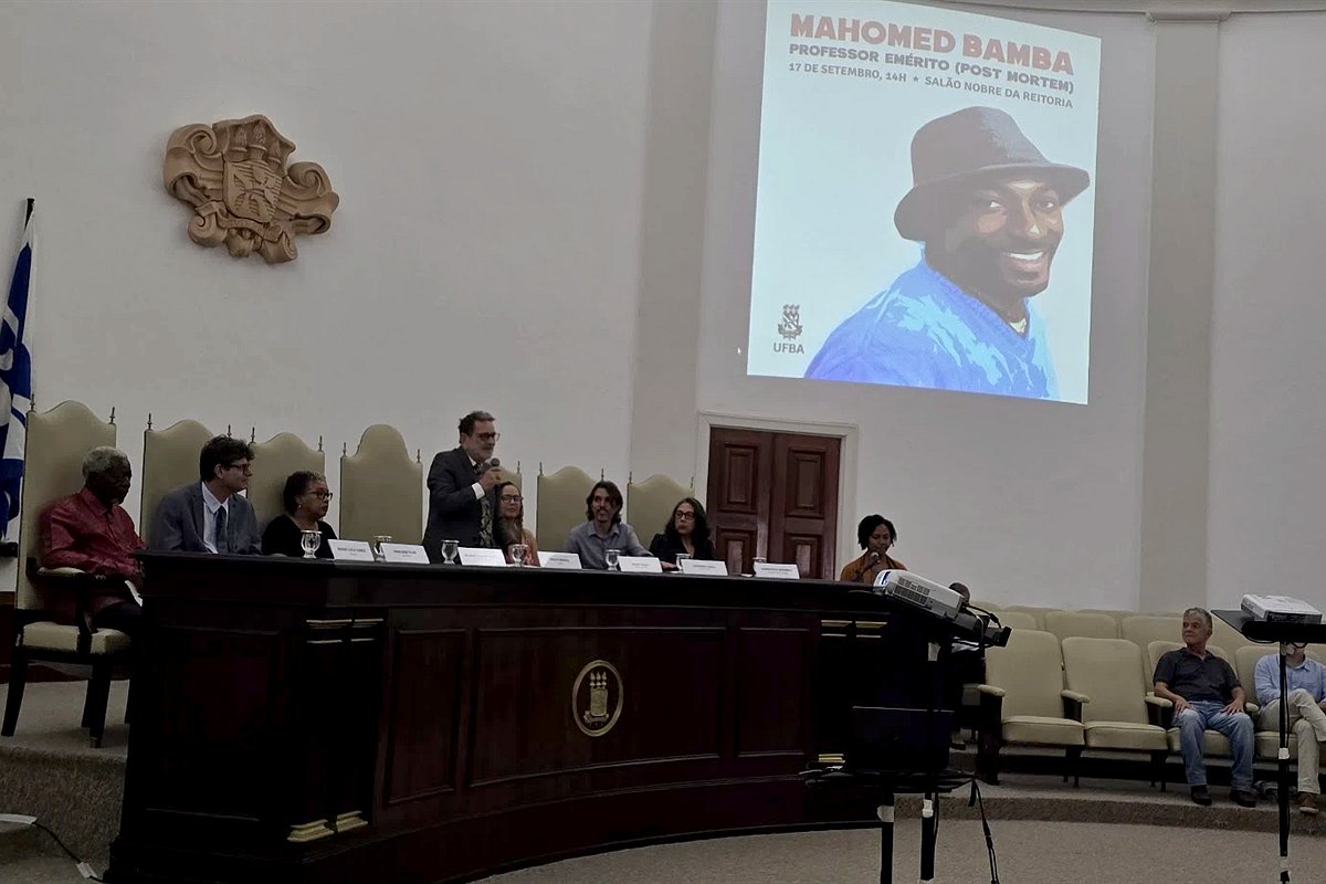 Sessão solene de outorga do título de Professor Emérito (post mortem) a Mahomed Bamba, no Salão Nobre da Reitoria da UFBA: mesa de autoridades e, ao fundo, a projeção com a foto do homenageado